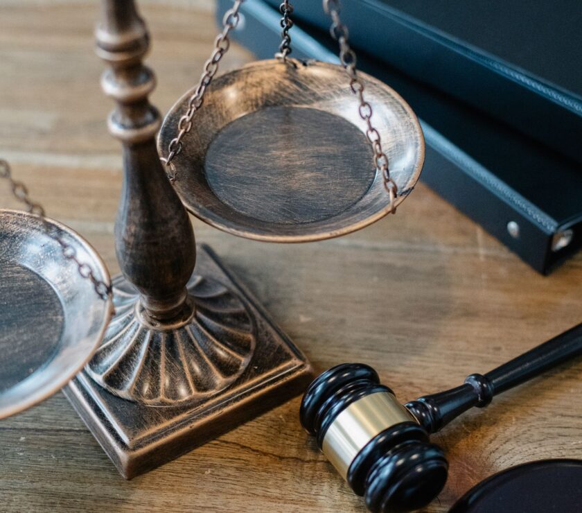 Balanza de la justicia, mazo y libros de derecho sobre mesa de madera